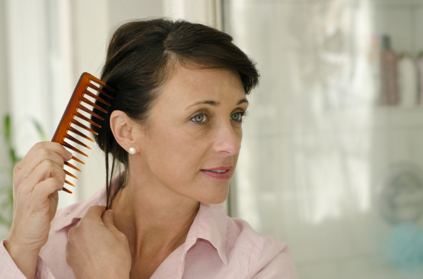 Pretty woman fixing her hair with a large tooth comb