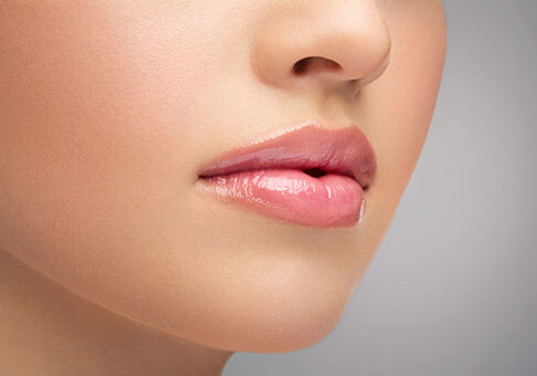 Close-up of smooth, glossy lips with natural pink makeup.
