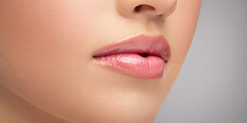 Close-up of smooth, glossy lips with natural pink makeup.